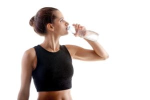 Sporty yoga girl on white background drinking water after practice