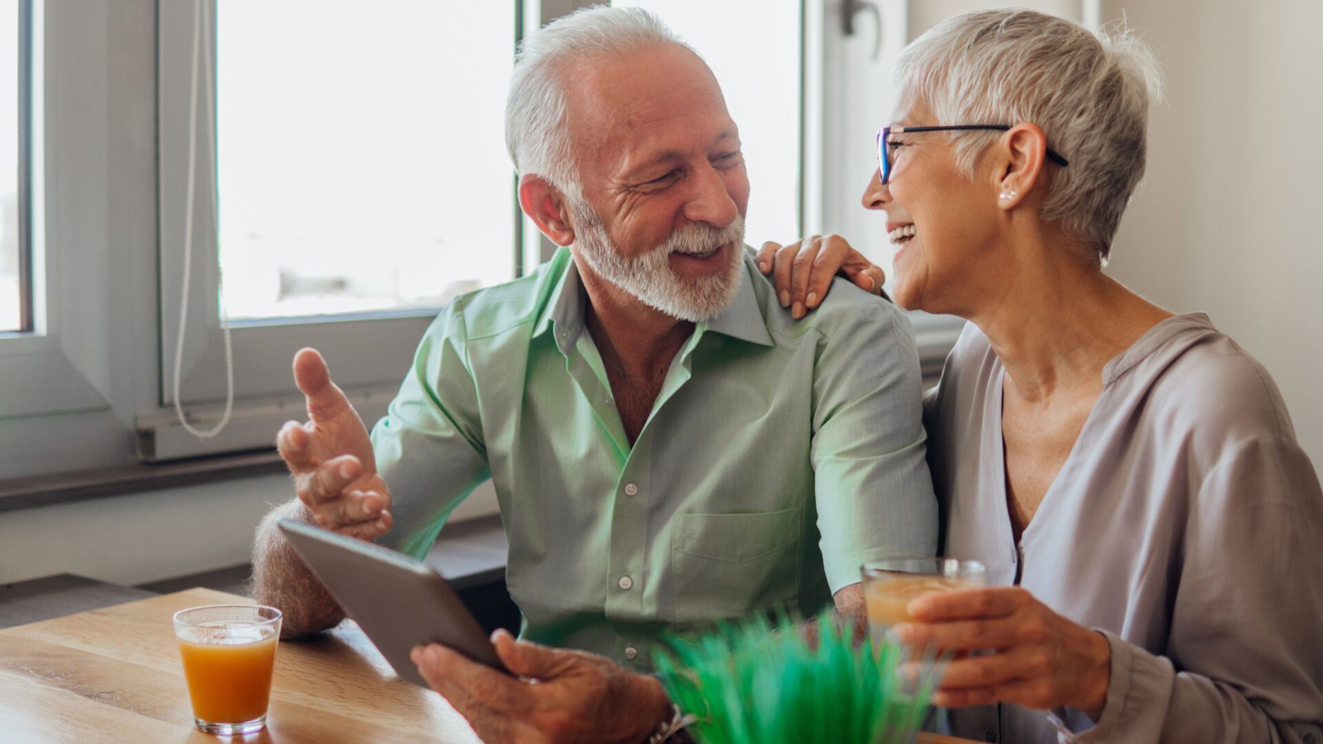 older couple smiling in front of a window